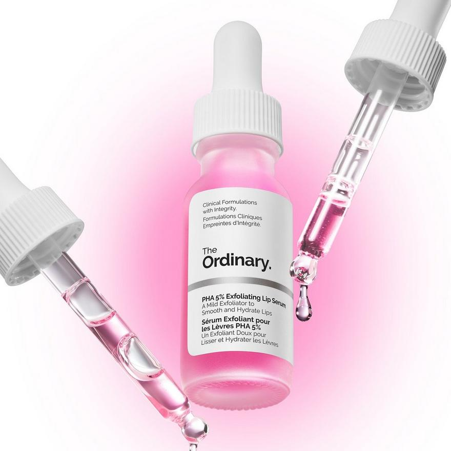 The Ordinary PHA 5% Exfoliating Lip Serum surrounded by dripping pink serum droppers on a bright pink glowing background.