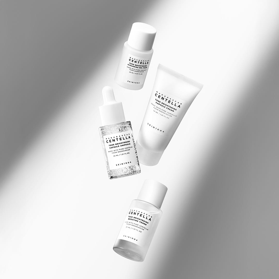SKIN1004 Tone Brightening Travel Kit cleansing gel foam, toner, ampoule and cream arranged with shadow lighting